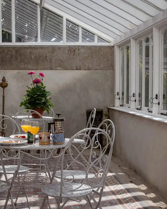 An iron table and chairs in the glass sunroom