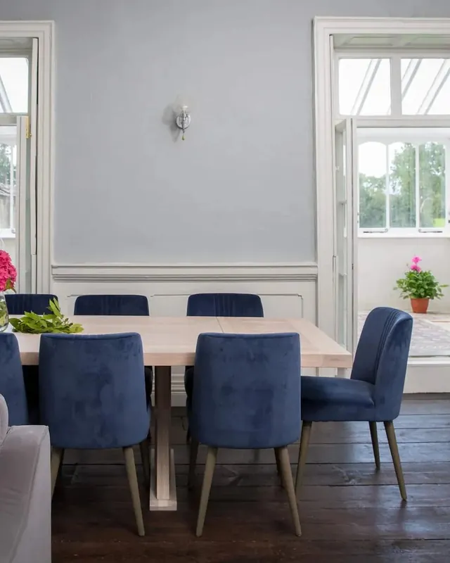 The long table in the dining room at Mountrothe House, with blue velvet chairs and tall windows